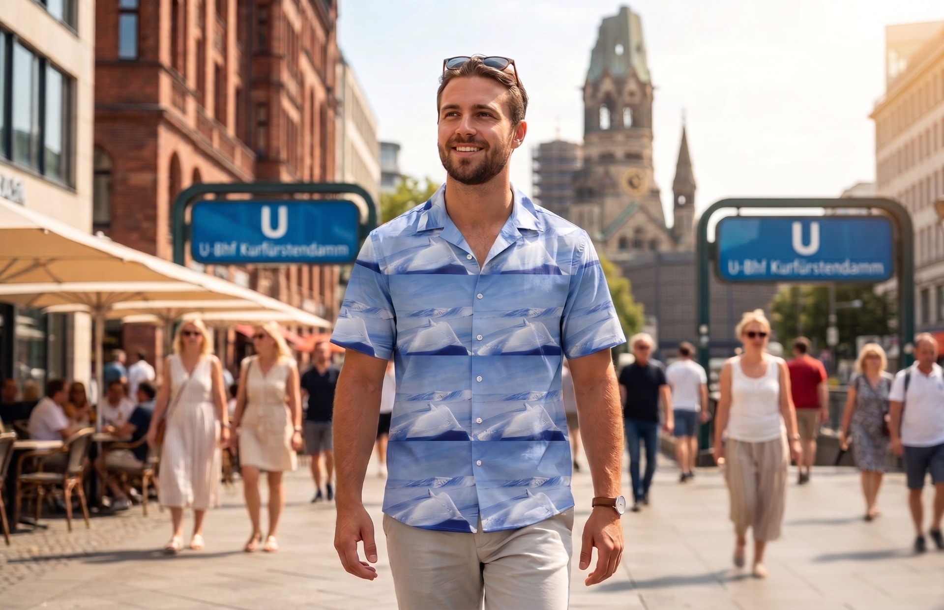 Man walking in front of a Berlin U-Bahn station wearing a light blue Arctropic shirt with a mountain print.